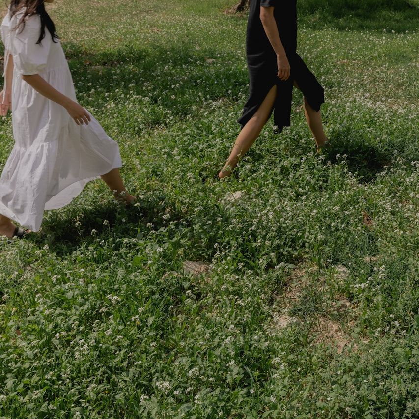 Two people walking through a grassy field with wildflowers