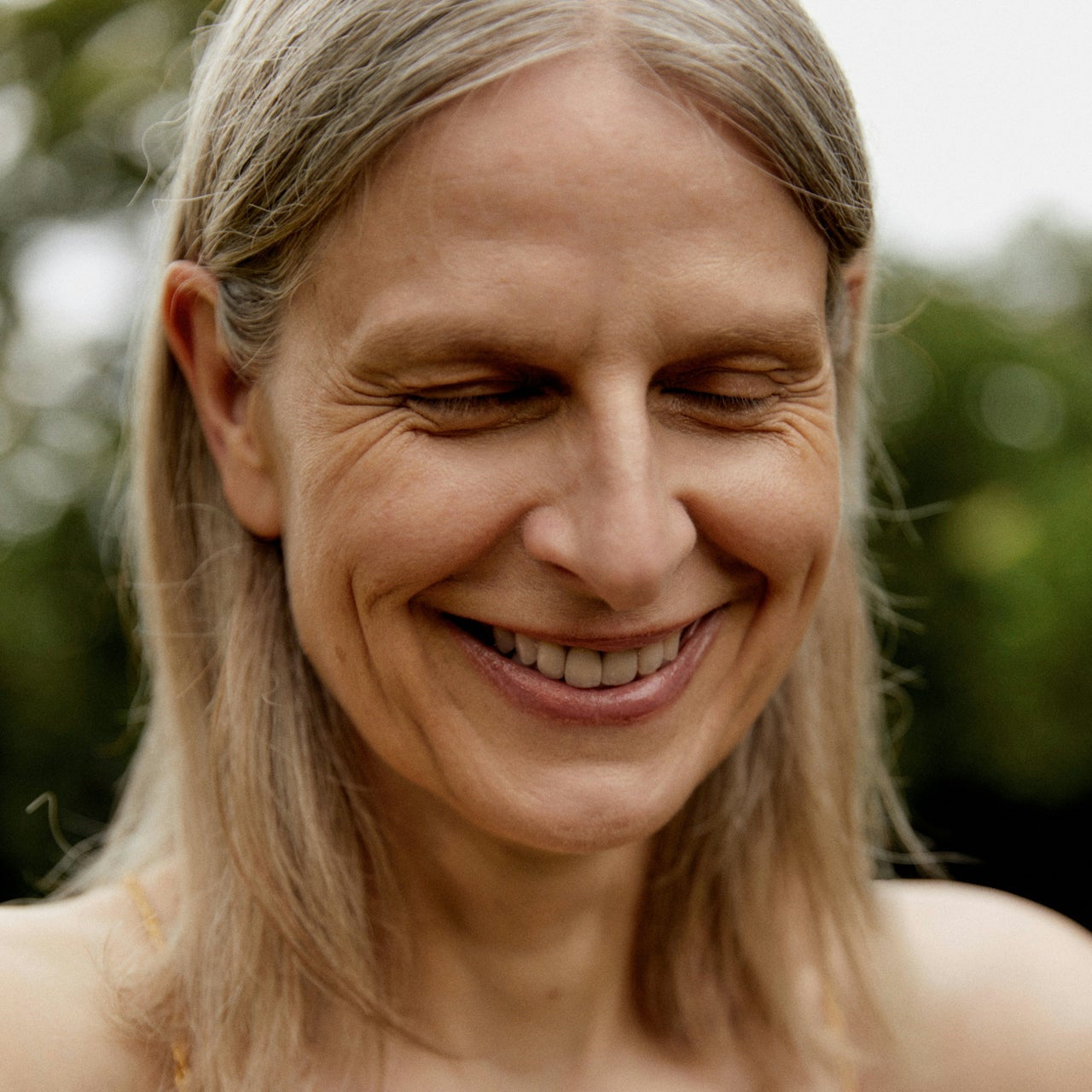 Woman with light-colored hair and a beige top outdoors